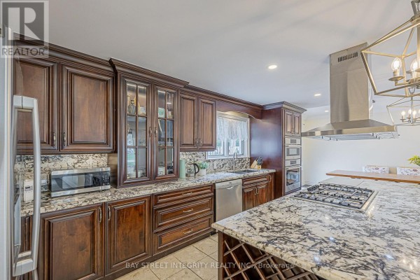 Kitchen with dark wood cabinets, granite counters, gas range, and island - 33 Deerford Road Toronto