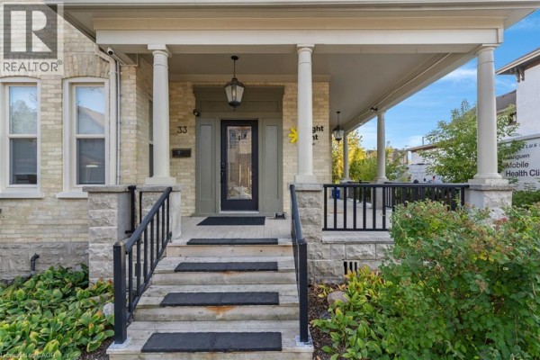 Close-up of the covered front porch with pillars, railings, and the building entrance. - 33 E Young Street E, Waterloo