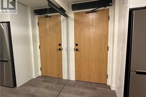 Entrance hallway with two light brown wooden doors and a large mirror. - 33 Erie Avenue Unit# 506, Brantford