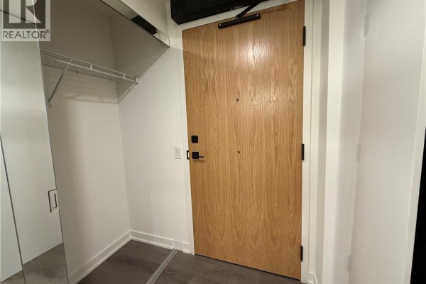 Apartment entrance with a closet on the left and a single wooden door. - 33 Erie Avenue Unit# 506, Brantford