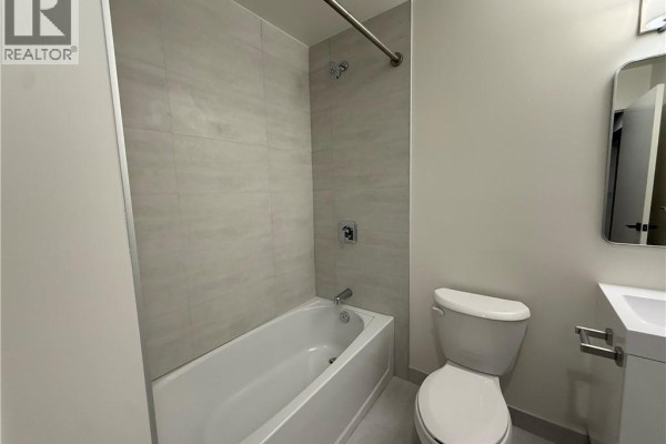 Close-up of a contemporary kitchen with white cabinets, stainless steel appliances, and a stone countertop. - 33 Erie Avenue Unit# 506, Brantford
