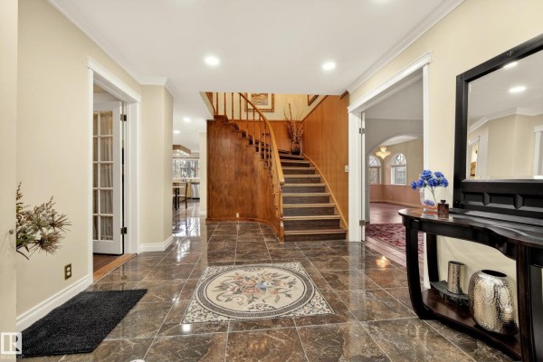 Foyer with dark tiled floors, a wooden staircase, and an inlaid circular mosaic. - 33 Glen Meadow Cr, St  Albert