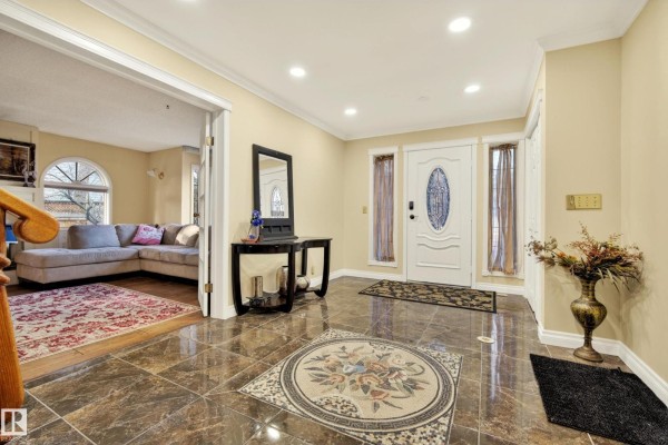 Spacious foyer with a white front door, mirrored console table, and view into living room. - 33 Glen Meadow Cr, St  Albert