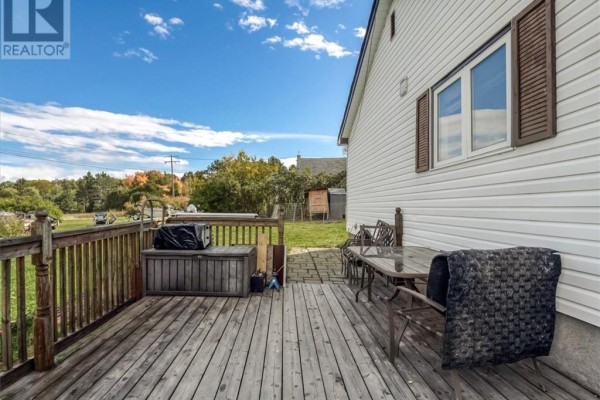 Wooden deck with patio furniture, storage chest, and railing, attached to the side of a white house. - 33 Graham Road, Whitefish