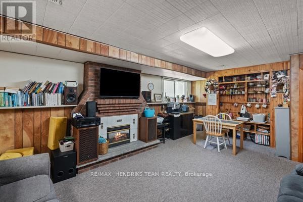 Basement living room with fireplace, TV, bookshelves, and dining table - 33 Meadowbrook Crescent St  Catharines