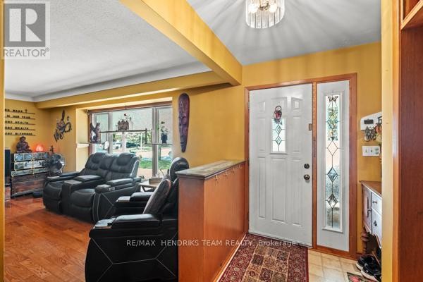 Interior view of a living room with black leather recliners and a white double front door. - 33 Meadowbrook Crescent, St  Catharines