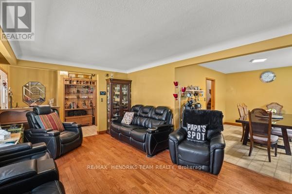Living room with black leather couches, wooden floors, and dining area - 33 Meadowbrook Crescent St  Catharines