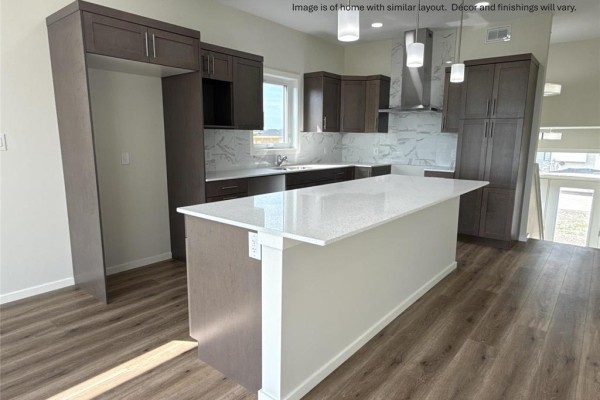 Modern kitchen with dark brown cabinets, white quartz island, and stainless steel appliances. - 33 Parkrose Place, St Adolphe
