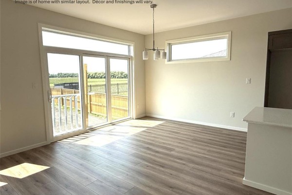 Dining area with large sliding glass doors opening to a fenced backyard. - 33 Parkrose Place, St Adolphe