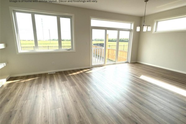 Living area with large windows and sliding glass doors showing a fenced backyard view. - 33 Parkrose Place, St Adolphe