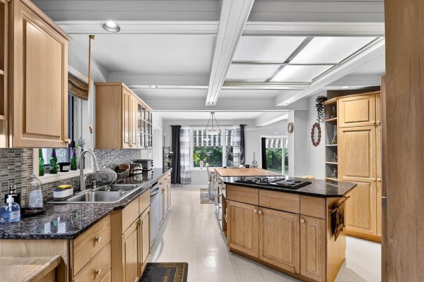 Dining room with a large wooden table and six chairs, a chandelier, and large windows overlooking the yard. - 33 River Crescent, Sanford