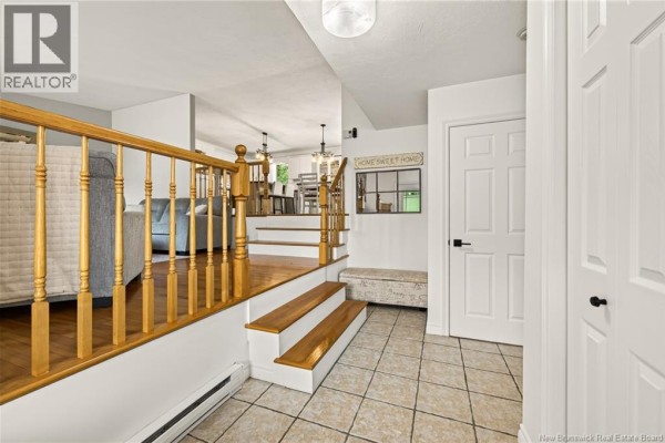 View from entryway showing split-level living area with wood floors and railings. - 33 Robichaud Court, Dieppe