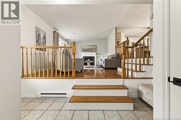 View of sunken living room with grey sofas, fireplace, and hardwood flooring. - 33 Robichaud Court, Dieppe