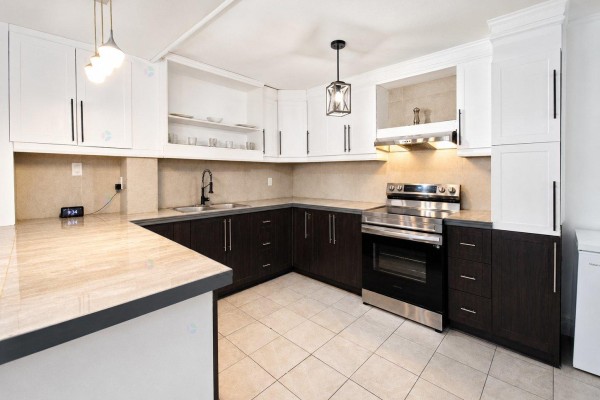 Kitchen with dark wood lower cabinets, white upper cabinets, stainless steel stove, and tiled floor. - 33 Rue De Dubuc, Gatineau