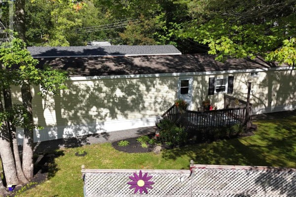 Aerial view of the side and rear of a beige mobile home with a wooden deck. - 33 Spring Crescent, Bridgewater