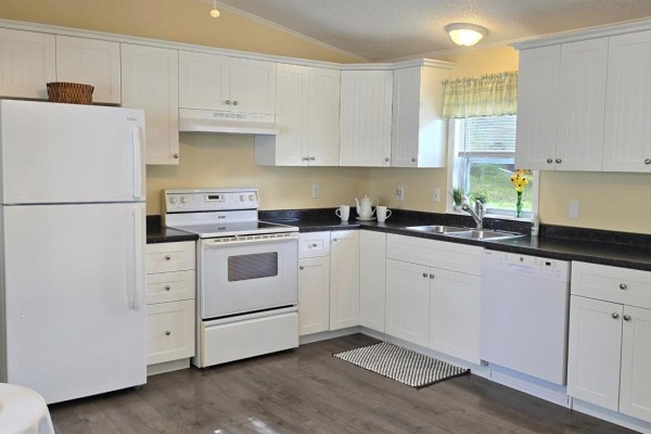 A spacious white kitchen with dark countertops, a white stove, and a large white refrigerator. - 33 Spring Crescent, Bridgewater