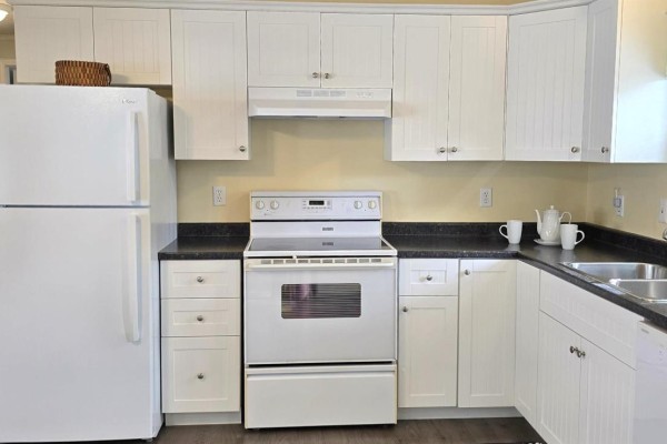A white kitchen with white cabinets, black countertops, a white stove, and a white refrigerator. - 33 Spring Crescent, Bridgewater