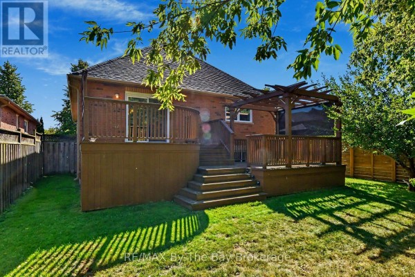 Backyard with wooden deck, stairs, and green lawn surrounded by fence. - 33 Telfer Road, Collingwood