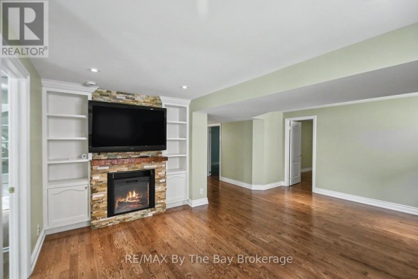 Living room with hardwood floors, fireplace, stone surround, and built-in shelving. - 33 Telfer Road, Collingwood