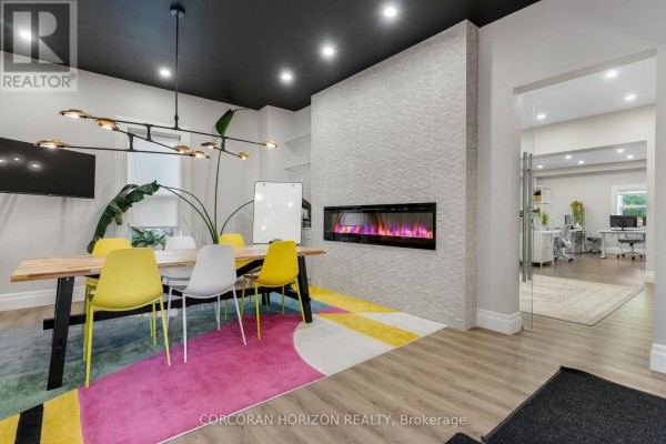 Conference room with a table, chairs, modern fireplace, and adjacent office space. - 33 Young Street, Waterloo