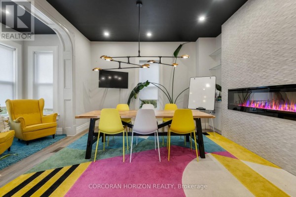 Meeting room with a dining table, colorful rug, yellow armchair, and electric fireplace. - 33 Young Street, Waterloo