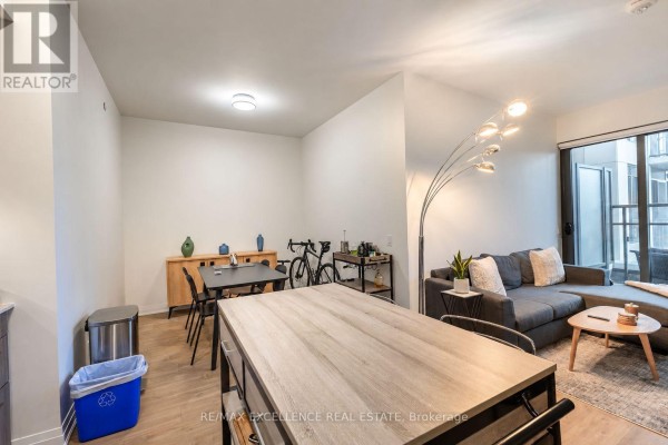 Open concept living and dining area with a large table, a bicycle, and a sectional sofa. - 330 - 280 Howland Avenue, Toronto