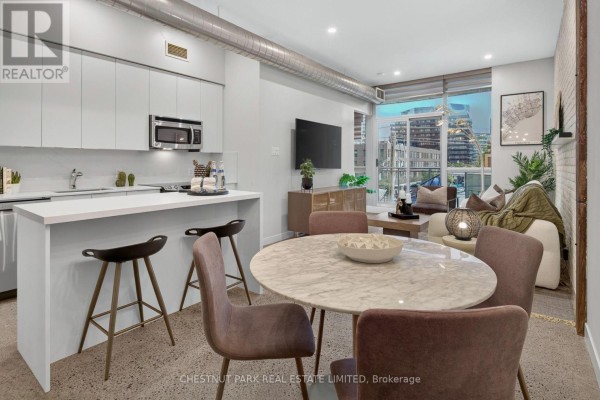 Open concept living area with kitchen island, dining table, and living room furniture. - 330 - 510 King Street E, Toronto