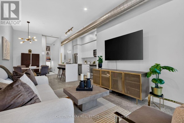 Living room showing sofa, television on a credenza, and entrance to kitchen area. - 330 - 510 King Street E, Toronto