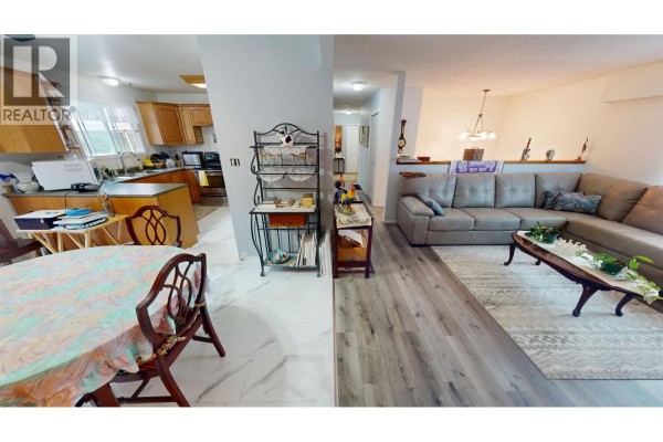 Open concept living area showing a large sectional sofa and a dining area adjacent to a kitchen. - 330 Caragana Road, Quesnel