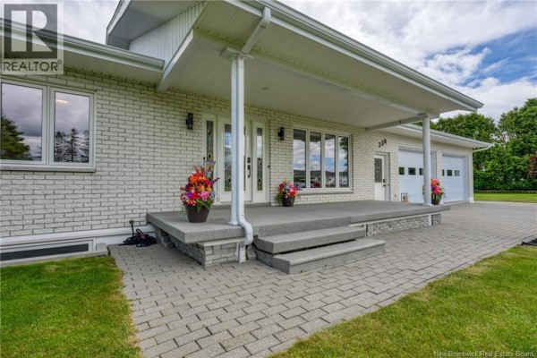 Front view of a white brick ranch-style house with a covered entryway and two garage doors. - 330 Guay Street, Grand Sault/grand Falls