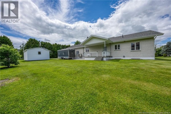 Modern white kitchen with a large island, black stools, stainless steel appliances, and a dining table. - 330 Guay Street, Grand Sault/grand Falls