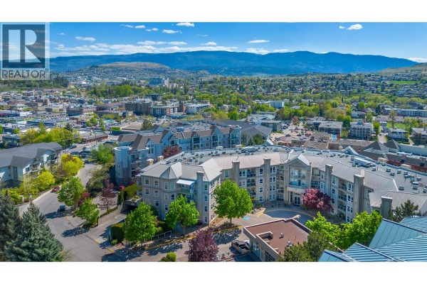Aerial view of the apartment building complex with surrounding town and mountains. - 3300 Centennial Drive Unit# 204, Vernon