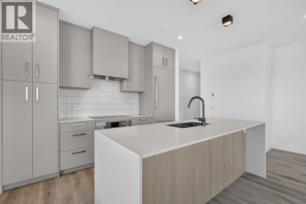 Kitchen with gray cabinets, quartz island, stainless steel appliances, and tiled backsplash. - 3300 Lakeshore Road Unit# 1303, Kelowna