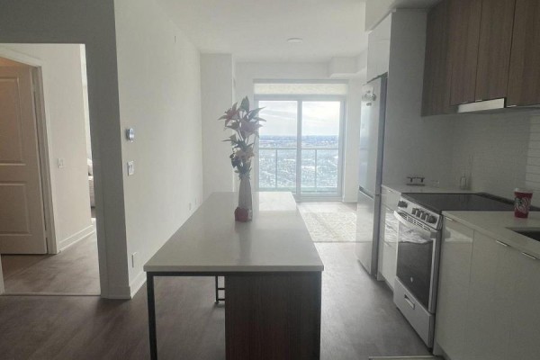 View of the kitchen and living area with a doorway leading to the bedroom. - 3303 - 30 Upper Mall Way, Vaughan