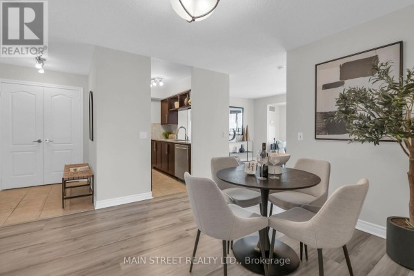 Dining area with a round table, four chairs, and view into the kitchen and hallway. - 3303 - 70 Town Centre Court, Toronto