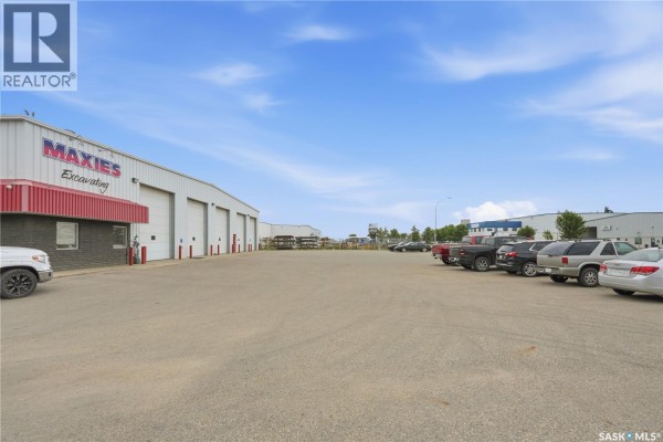 View of a paved lot with parked vehicles in front of a commercial building on a sunny day. - 3303 Faithfull Avenue, Saskatoon