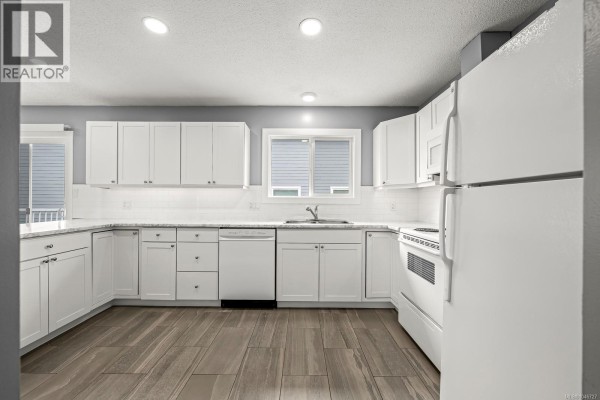 White kitchen with marble-look countertops, white cabinets, and a sliding glass door leading to a deck. - 3303 Seventh St, Cumberland