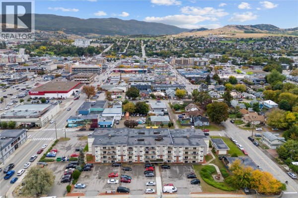 Daytime aerial view of Vernon, highlighting urban layout and nearby mountains. - 3304 35th Avenue Unit# 215, Vernon