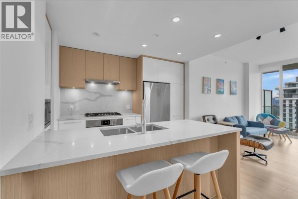 Open concept kitchen and living area with a blue sofa, chairs, and a view of the city. - 3305 567 Clarke Road, Coquitlam