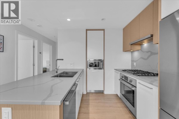 Kitchen island with double sink, and a view of the hallway and a built-in microwave. - 3305 567 Clarke Road, Coquitlam