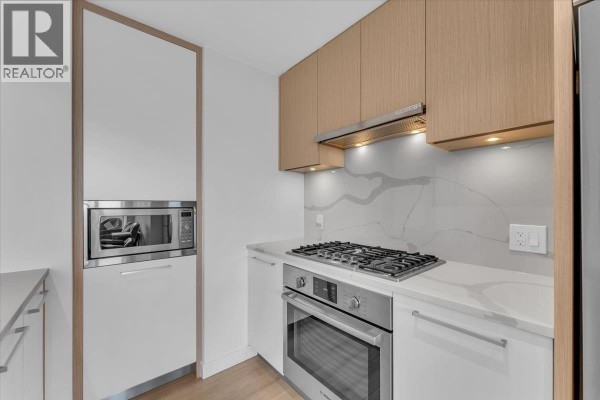 Kitchen features stainless steel appliances, gas stovetop, quartz backsplash, and light wood cabinetry. - 3305 567 Clarke Road, Coquitlam