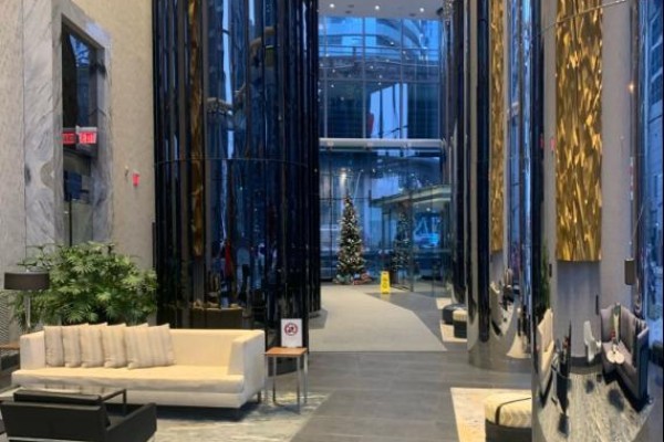 A spacious building lobby with seating areas, tall reflective columns, and a Christmas tree in the distance. - 3306 - 10 York Street, Toronto