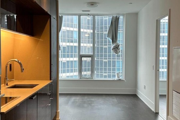 Apartment living space with dark hardwood floors and a large window overlooking city buildings. - 3306 - 10 York Street, Toronto