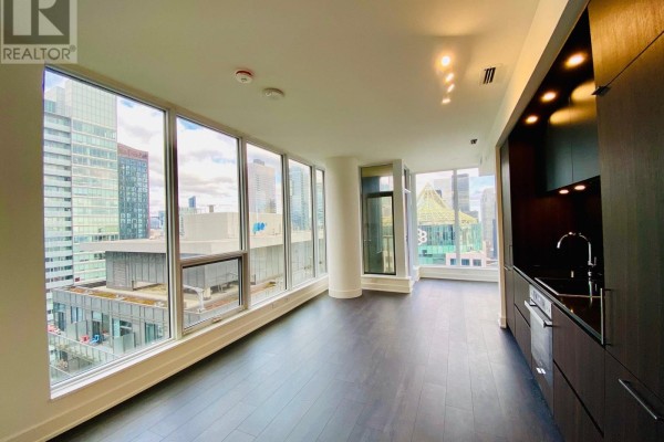 Bright living area with floor-to-ceiling windows and dark wood flooring. - 3306 - 15 Mercer Street, Toronto