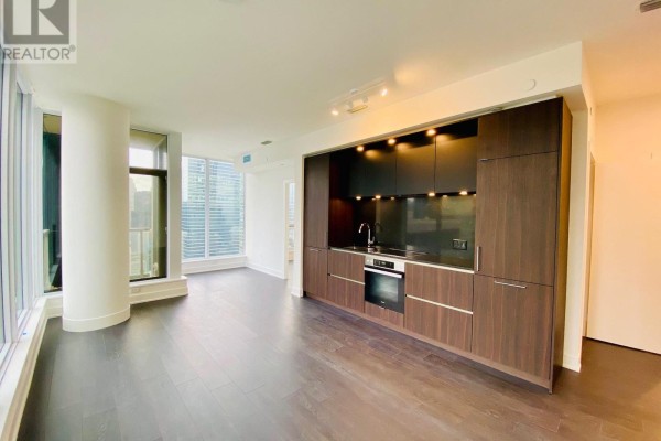Open-concept living space with a modern kitchen and dark wood cabinetry. - 3306 - 15 Mercer Street, Toronto