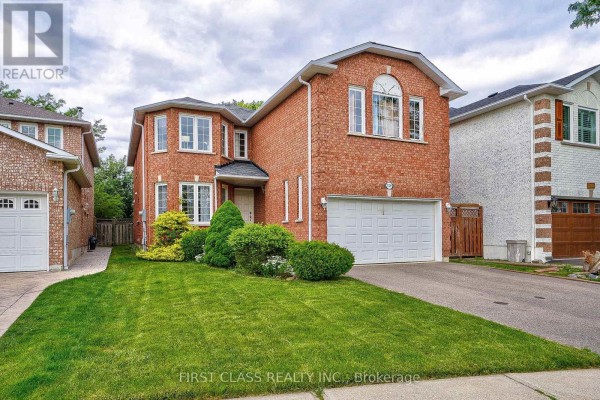 Side exterior view of a red brick two-story house with a lawn, bushes, and a paved driveway. - 3309 Loyalist Drive, Mississauga