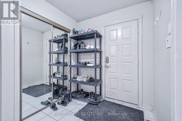 Interior foyer with a large mirror, shoe storage shelves, and a white paneled front door. - 3309 Loyalist Drive, Mississauga