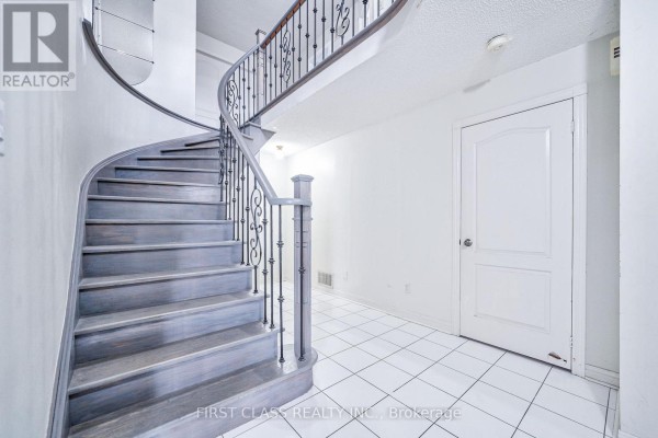 Interior view of a grand staircase with a black metal railing and grey wood steps. - 3309 Loyalist Drive, Mississauga