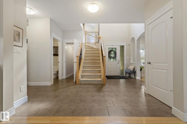 Interior foyer with a staircase, tiled flooring, and arched doorways. - 331 Callaghan Cl Sw, Edmonton