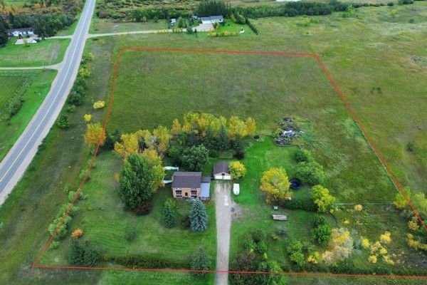 Aerial drone view showing the property lot with a house, garage, and surrounding fields. - 331 Memorial Drive, Rivers